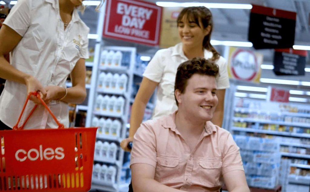 Quality Progressive Care team helping a man with disabilities through coles supermarket